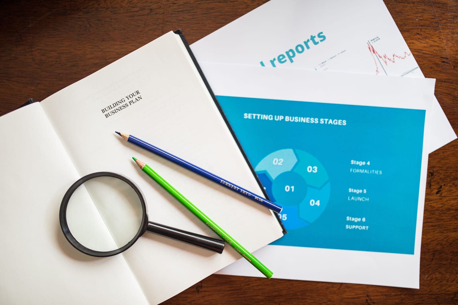 A business plan workbook open beside a printed setup-stages report
